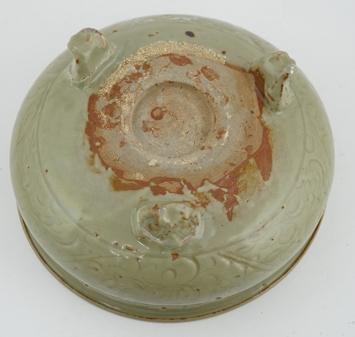 A Chinese Ming Longquan celadon tripod censer, 14th/15th century, the exterior incised with scrolling foliage, on three animal mask feet, burnt orange ring to base, 26.7cm diameter, original receipt for Wing Kei curios,